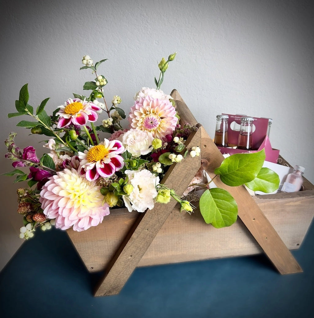 A beautiful handmade wooden gift basket filled with flowers, Sealuxe spa products, TÖST non-alcoholic sparkling teas, and hand soap from handmade la conner. Daily delivery available by Seattle florist Campanula Design Studio