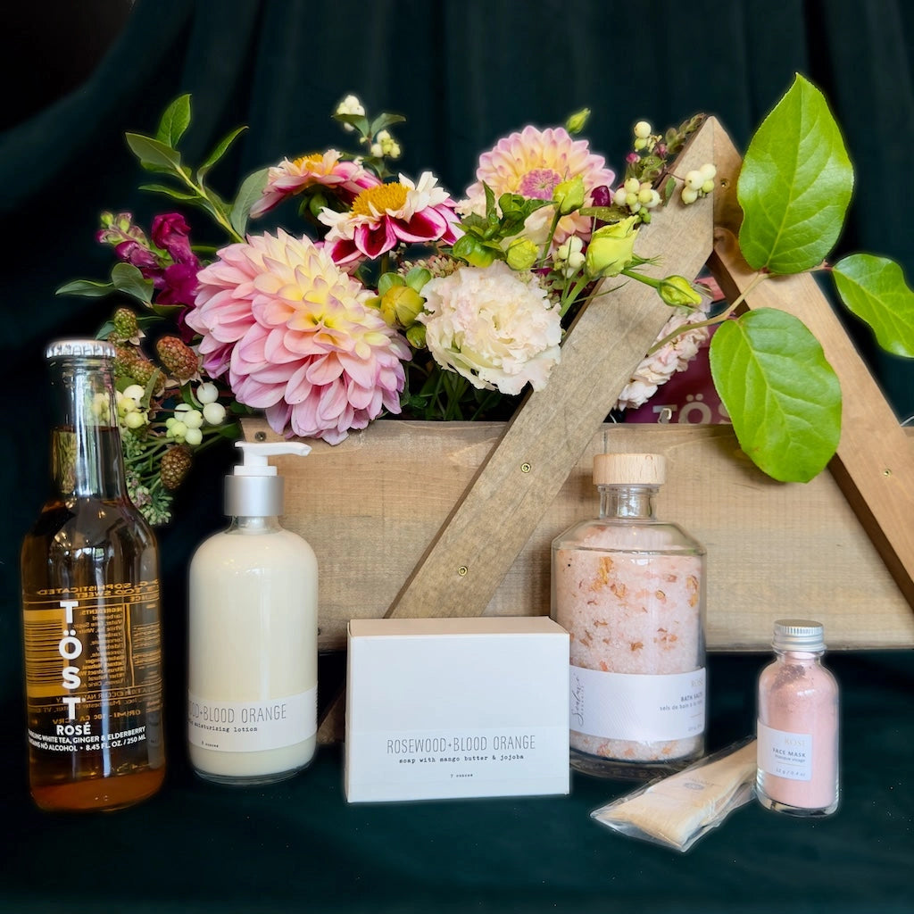 A beautiful handmade wooden gift basket filled with flowers, Sealuxe spa products, TÖST non-alcoholic sparkling teas, and hand soap from handmade la conner. Daily delivery available by Seattle florist Campanula Design Studio