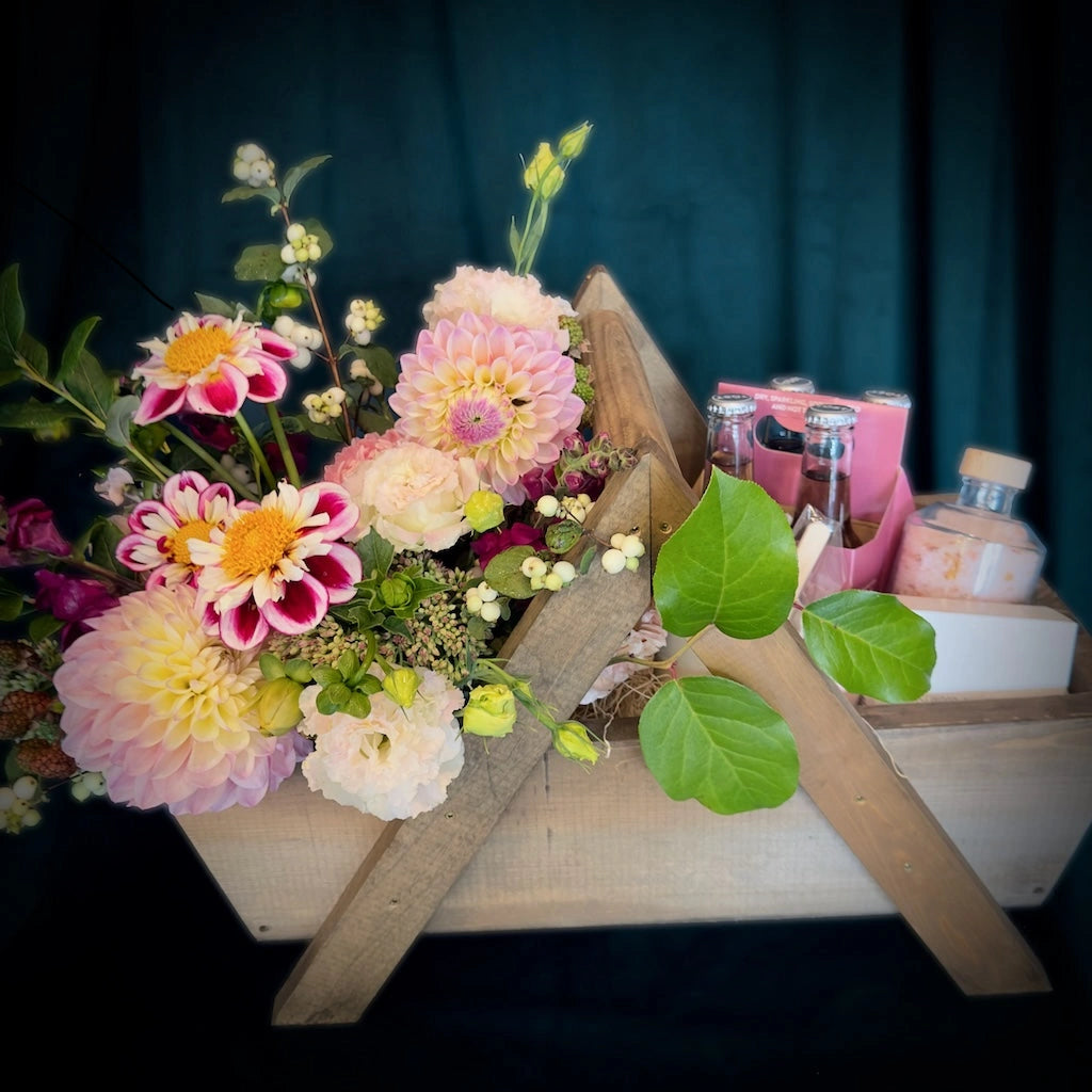 A beautiful handmade wooden gift basket filled with flowers, Sealuxe spa products, TÖST non-alcoholic sparkling teas, and hand soap from handmade la conner. Daily delivery available by Seattle florist Campanula Design Studio