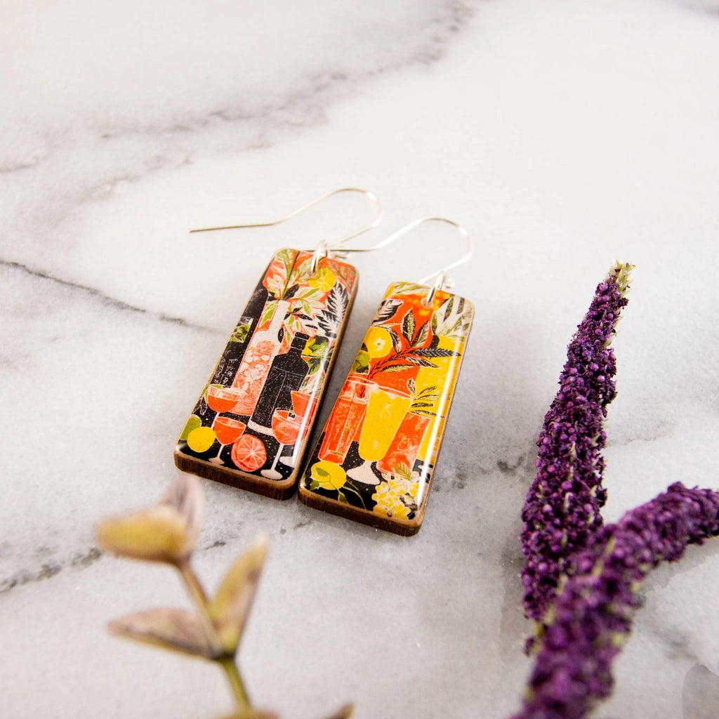 Shaken, not stirred! These delightful earrings are the perfect summer accessory. Featuring a retro style cocktail party illustration, rendered in shades of orange, yellow, green and black. Available from Seattle's best flower shop, Campanula Design Studio for nationwide shipping, shop pick-up, or delivery in the greater Seattle area. Combine these with one of our flower arrangements, gift baskets, or houseplants for the perfect gift.