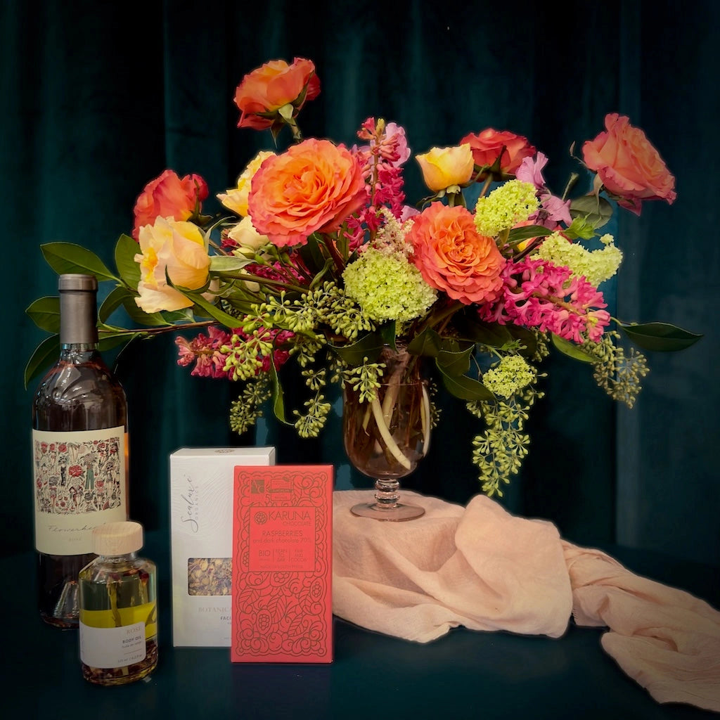 A dozen beautiful Garden Roses in a clear vase with a bottle of wine, some chocolate and spa products. Available from Campanula Design Studio in Seattle, WA. 