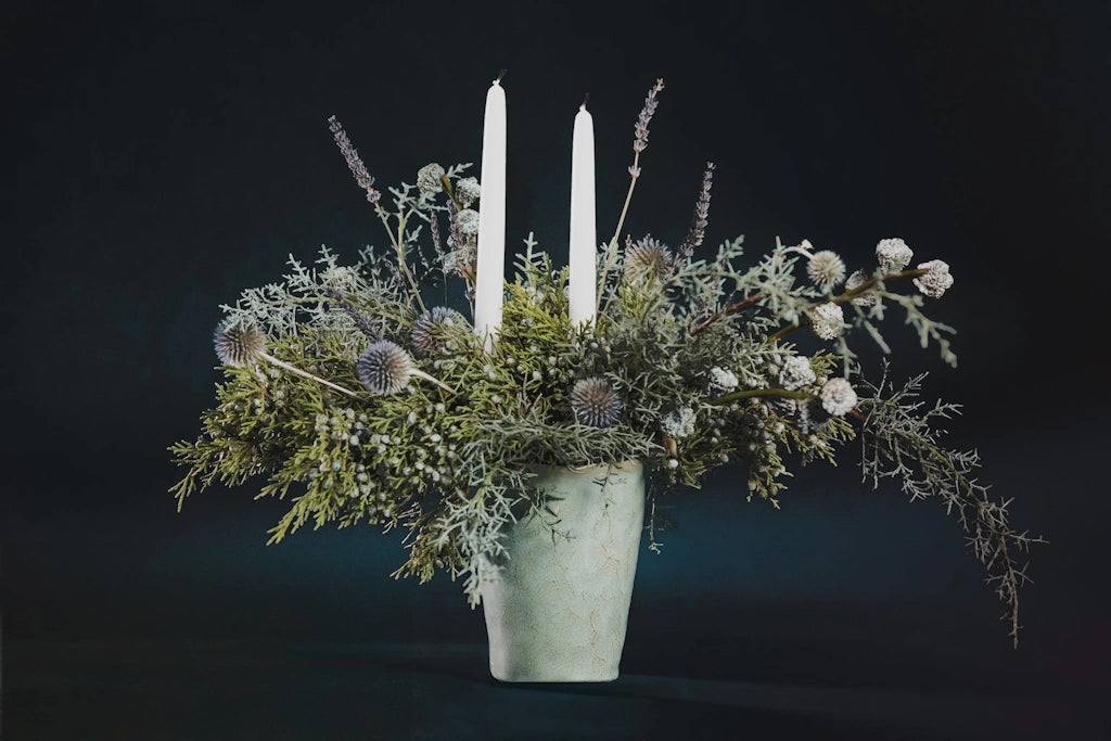 Designed with premium evergreens, dried flowers, and taper candles in a simple ceramic vase, this beautiful holiday centerpiece will last throughout the season. From Campanula Design Studio for Seattle flower delivery!