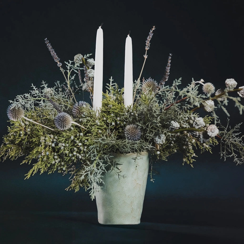 Designed with premium evergreens, dried flowers, and taper candles in a simple ceramic vase, this beautiful holiday centerpiece will last throughout the season. From Campanula Design Studio for Seattle flower delivery!