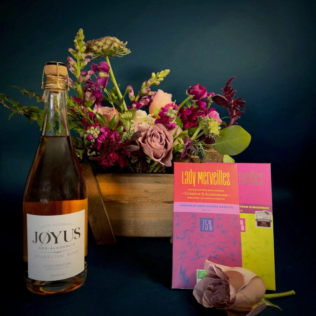 A floral gift basket featuring non-alcoholic wine, award winning chocolate, and a seasonally inspired floral designed in a handmade wooden gift basket by Seattle Florist Campanula Design Studio. 