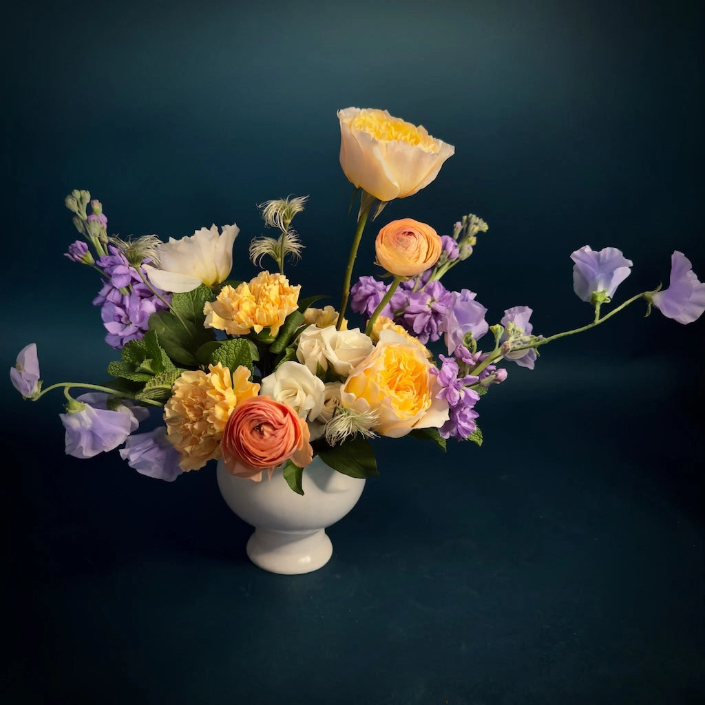 We're smitten with this sweet floral design of sunny yellows, soft lavenders, creamy whites, and oranges designed in a simple ceramic compote. That's why we called it "Smitten". We think you'll be smitten too. Available for delivery in the greater Seattle area. Perfect for Valentine's Day or any day!