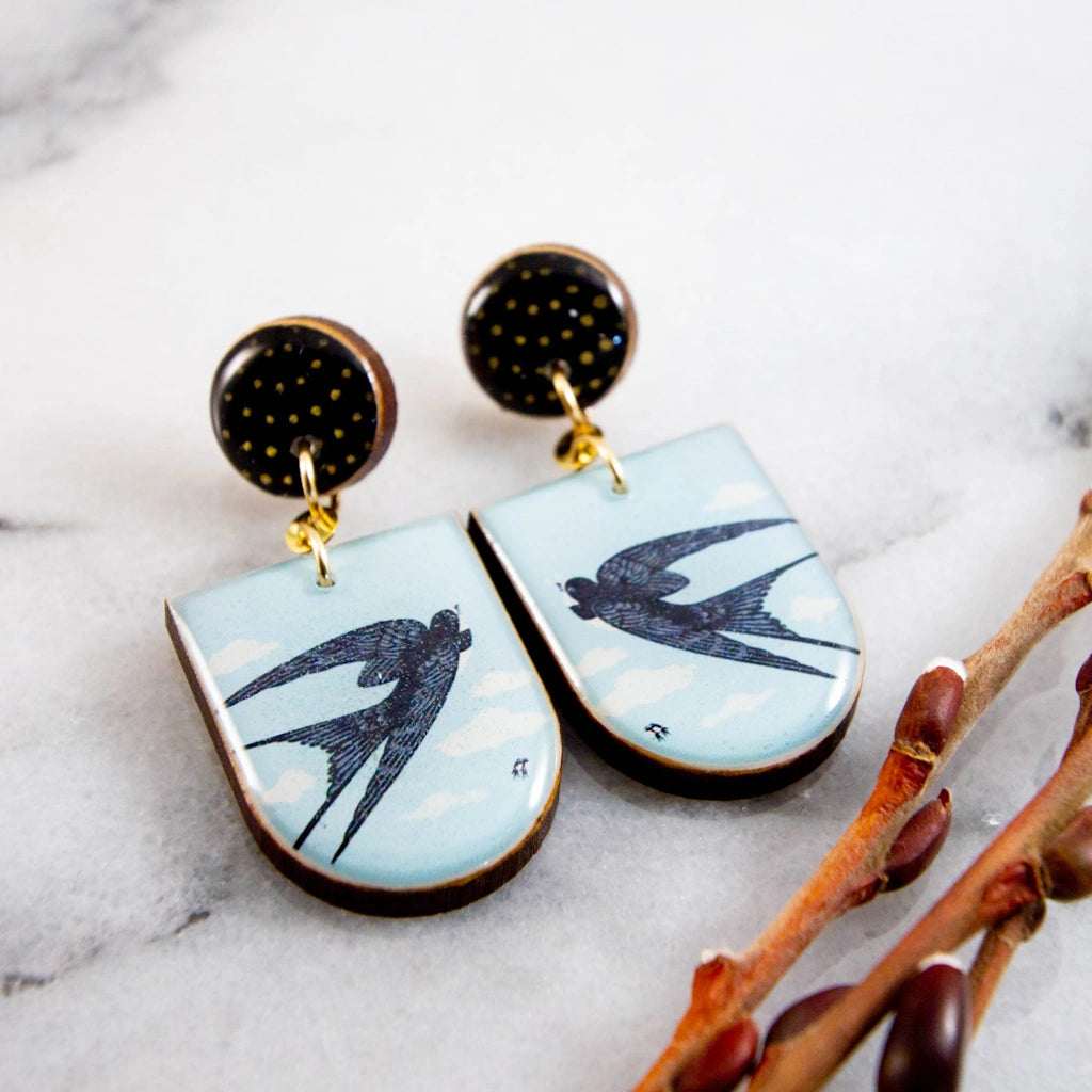 These charming earrings are the perfect spring accessory! Featuring a sweet vintage swallow illustration, rendered in soft blue and crisp black. Made from sustainably sourced North American hardwood and finished with soy-based, BPA/VOC free resin, these vibrant earrings will bring joy and brightness to any wardrobe. Surgical steel post earrings. Approximately 1.7 inches long.