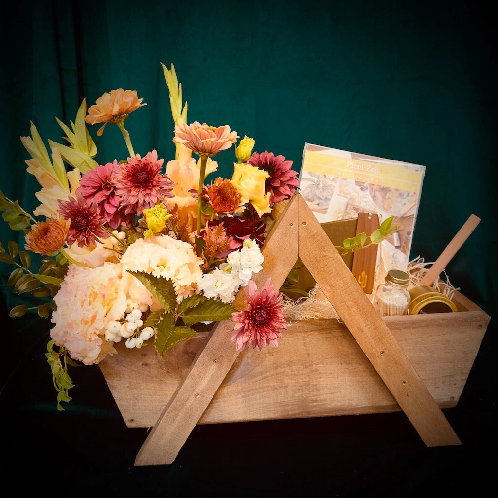 Our "Zen Garden" gift basket contains an adult watercolor kit, journaling supplies, a candle and a beautiful, seasonal floral from Seattle Florist, Campanula Design Studio.